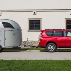 Czerwony SUV ciągnie przyczepę z wizerunkiem konia.